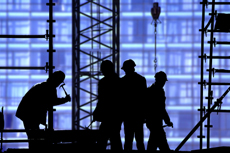 silhouettes of hard hat workers on construction project