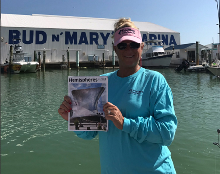 Woman holding up magazine at a marina